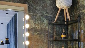 Ein Badezimmer mit Waschtisch, einem beleuchteten Spiegel, einem Handtuchregal und einem dekorativen Korb.