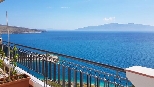 Ein Balkon mit Blick auf das Meer und ferne Berge.