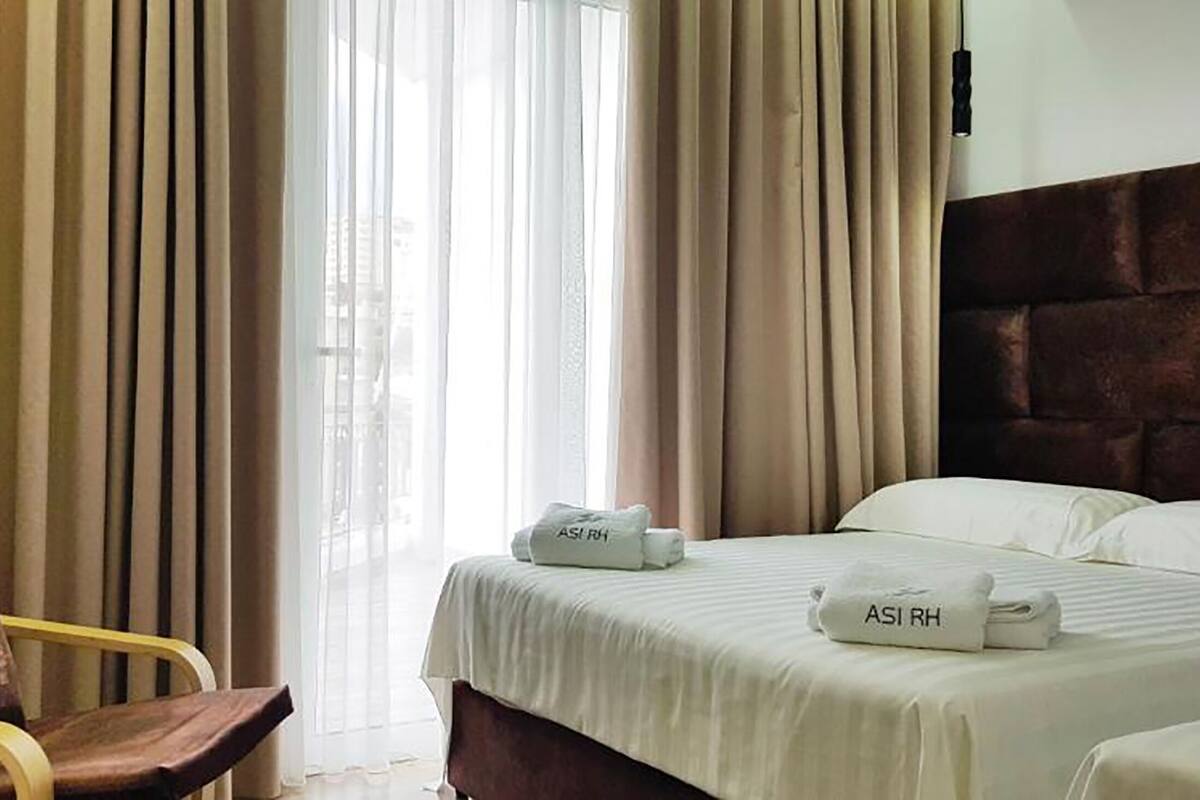 Habitació d'hotel amb un llit, una cadira i cortines.