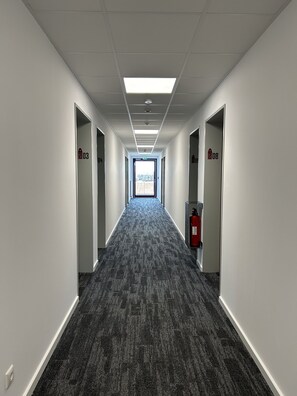 A long, narrow hallway with carpeted floors, white walls, and doors numbered 203 and 208. - STAHLTOWER (Friesoythe)