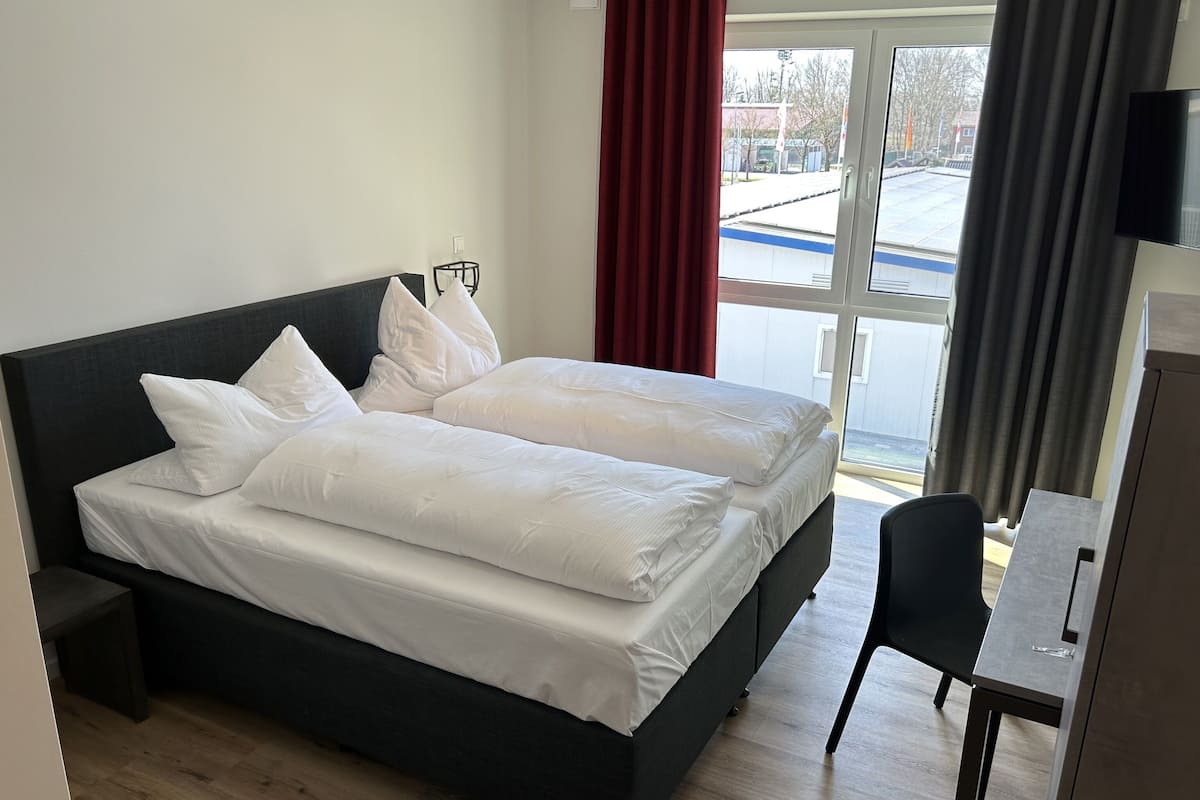 A double bed with white linens, a dark headboard, and a small bedside table.