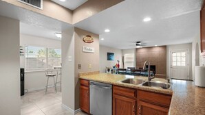 A modern kitchen with granite countertops, stainless steel appliances, and wooden cabinets. - This spacious home has all you need with 2 primary suites, 2 guest bedrooms, and 3 bathrooms. There is no shortage of living space with a living room, 2 dining rooms, open floor plan w/fully-stocked kitchen, and onsite laundry. (El Paso)