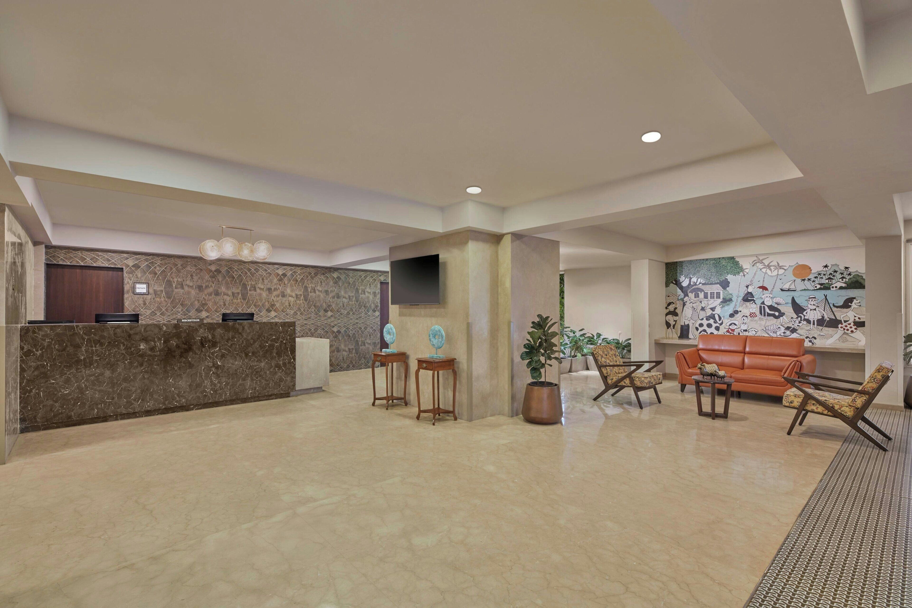 A spacious lobby with a reception desk, seating area, and a mural on the wall.