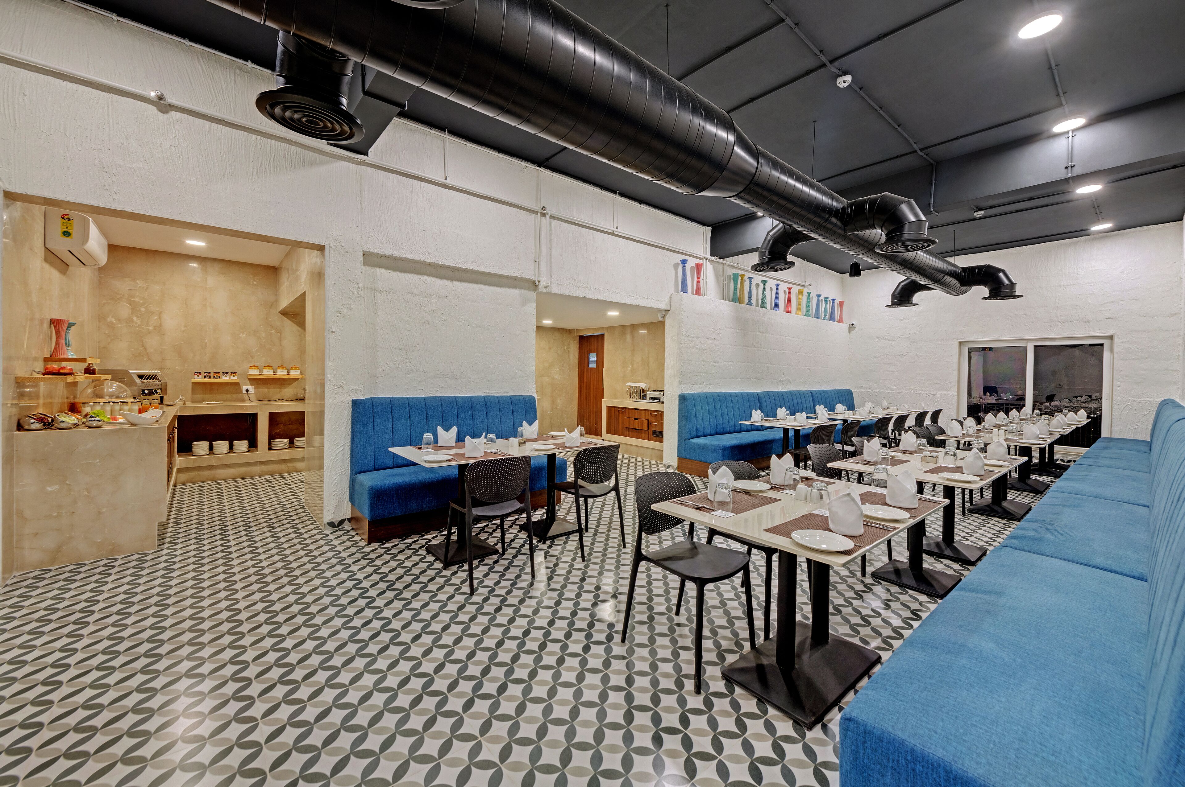 A modern restaurant with blue seating, white walls, and a patterned floor.