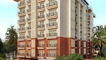 A multi-story hotel with balconies, a sign indicating 'The Fern Hotel, Candolim, Goa'.