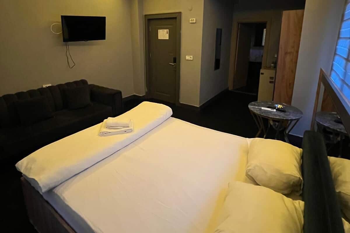 Une chambre d’hôtel avec un lit, un téléviseur fixé au mur, un canapé et une petite table.