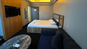Ett hotellrum med en säng, en soffa, en tv och ett litet bord.