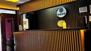Ett väntrum med en väggpanel av träribbor, en klocka och en neonskylt.