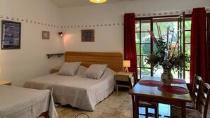 A bedroom with a bed, bedside tables, a window with curtains, and a view of greenery outside. - Gîte Studio with Terrace in Venasque (Venasque)