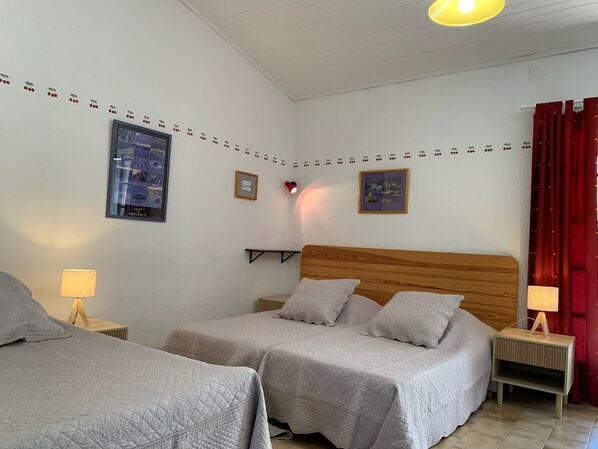 Una habitación de hotel con dos camas, cabecero de madera, una repisa pequeña y cortina roja.