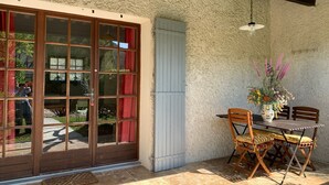 A patio with a table and chairs, a door with glass panels, and a textured wall. - Gîte Studio with Terrace in Venasque (Venasque)