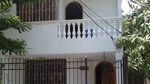 A white building with a gated entrance, a balcony with balustrades, and a window with decorative iron bars. - Room in House - Taminaka Hostel en Santa Marta - Shared Room 2 (Santa Marta)