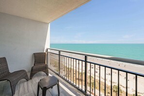 A balcony with wicker chairs and a table, overlooking a beach with a clear view of the ocean. - Direct View on Boardwalk, Centrally Located, Pools (Myrtle Beach)