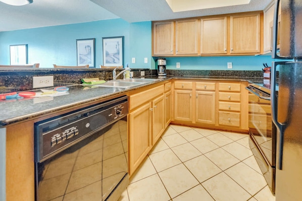 A kitchen with wooden cabinets, a dishwasher, and a refrigerator. - Direct View on Boardwalk, Centrally Located, Pools (Myrtle Beach)