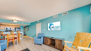 Un salon avec un coin repas, une cuisine à l’arrière-plan et une enseigne indiquant « Big Fish Rentals ».
