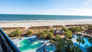 Ein Resort mit großzügigem Poolbereich, Blick auf einen Strand und einem Sandstrand.