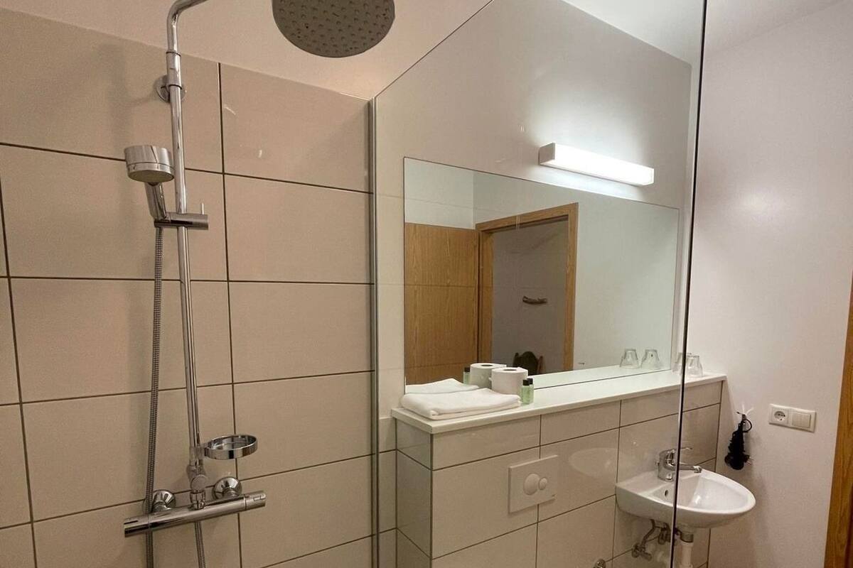Un baño moderno con cabina de ducha de vidrio, inodoro, lavabo y espejo.