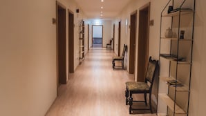 A long, narrow hallway with wooden flooring and a bookshelf on the right. - Hotel Studlagil  (Egilsstaðir)
