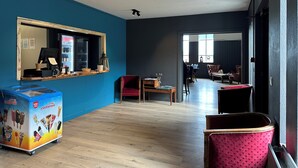 A modern interior with a blue wall, a vending machine, a wooden counter, and a seating area with chairs and a table. - Hotel Studlagil  (Egilsstaðir)