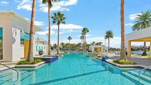 A large outdoor swimming pool surrounded by palm trees and modern buildings with blue accents. - Carillon Beach Inn 307, Pet Friendly!, 1BD/1BA , Beautiful Resort! (Panama City Beach)
