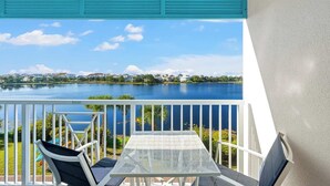 A balcony with a view of a lake, white railing, and a table with chairs. - Carillon Beach Inn 307, Pet Friendly!, 1BD/1BA , Beautiful Resort! (Panama City Beach)