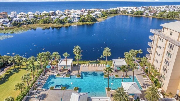 A resort with a large swimming pool, palm trees, and a view of the ocean. - Carillon Beach Inn 307, Pet Friendly!, 1BD/1BA , Beautiful Resort! (Panama City Beach)