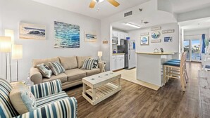 A modern living room with a sofa, striped armchairs, a wooden coffee table, and a ceiling fan. - Carillon Beach Inn 307, Pet Friendly!, 1BD/1BA , Beautiful Resort! (Panama City Beach)