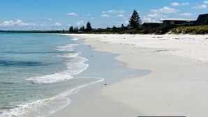 Una spiaggia con acque cristalline, una riva sabbiosa e edifici sullo sfondo.