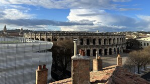 A view of an ancient aqueduct with a modern building in the foreground.