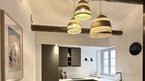 A modern kitchen with dark cabinetry, a herringbone wood floor, and pendant lighting.