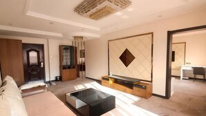 Habitación de hotel moderna con sofá, mesa de centro, televisor, armario y espejo.