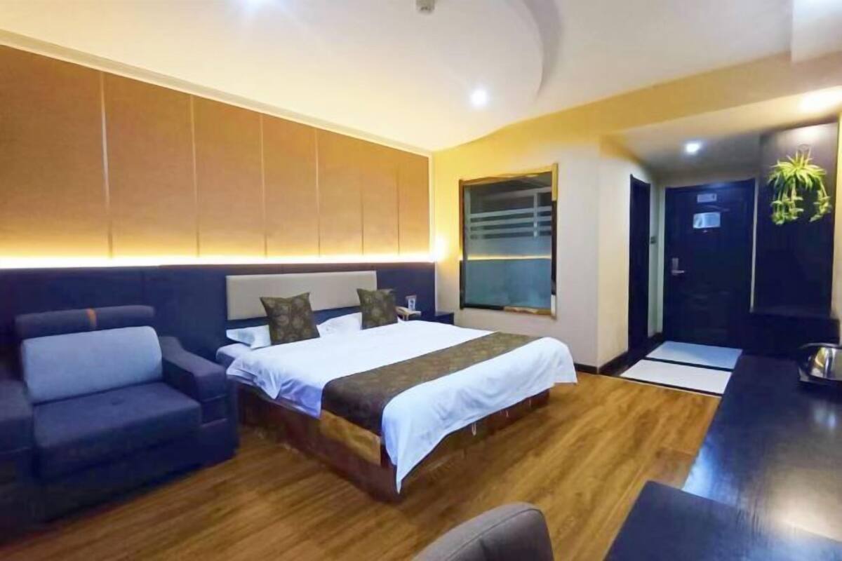 A hotel room with a bed, a sofa, a desk, and a window.