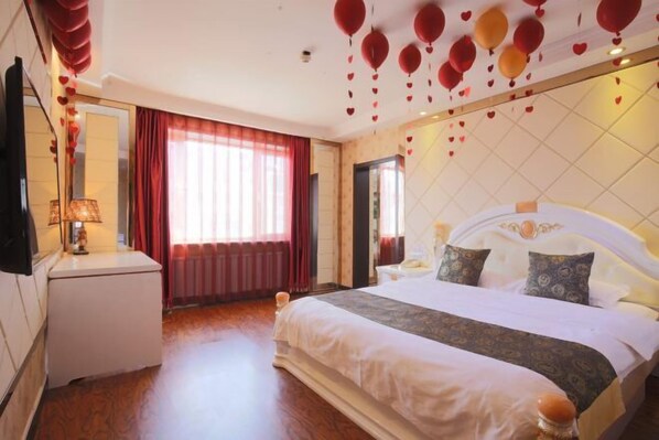 A hotel room with a large bed, a bedside table, a lamp, and a view of the outside through a window with red curtains. - Dunhua Service Building Hotel (Dunhua)