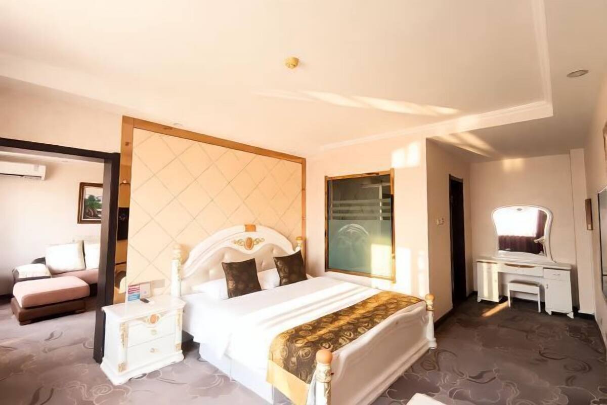 A hotel room with a bed, bedside tables, a desk, and a chair.