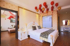 A bedroom with a large bed, a bedside table, a dresser, and a desk with a chair. - Dunhua Service Building Hotel (Dunhua)