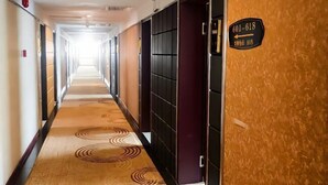 Un pasillo de hotel con alfombra estampada, un cartel que indica las habitaciones 601 a 618, y una puerta a la derecha.