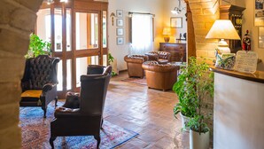 Un hall d’entrée accueillant, agrémenté d’une arche en pierre, de poutres en bois, d’un comptoir de réception et de sièges confortables.