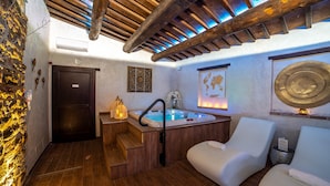 Une salle de spa avec un plafond en bois, un jacuzzi et deux chaises blanches.