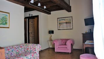 A living room with a floral sofa, a pink armchair, a wooden coffee table, and a television.