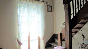 Una habitación con escalera de madera, alfombra estampada y sofá floral.