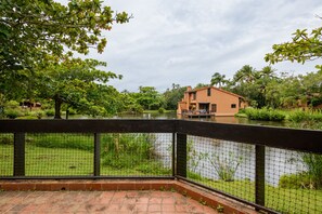 Une maison avec un étang devant, entourée de verdure et d’une clôture.
