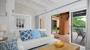 A modern living room with a white sofa, a wooden coffee table, and a view of the outdoor patio area.