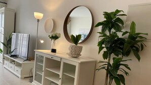 A white cabinet with glass doors, a round mirror, a potted plant, and a floor lamp. - Marassi Marina 2 bedroom pool view 403 (El Alamein)