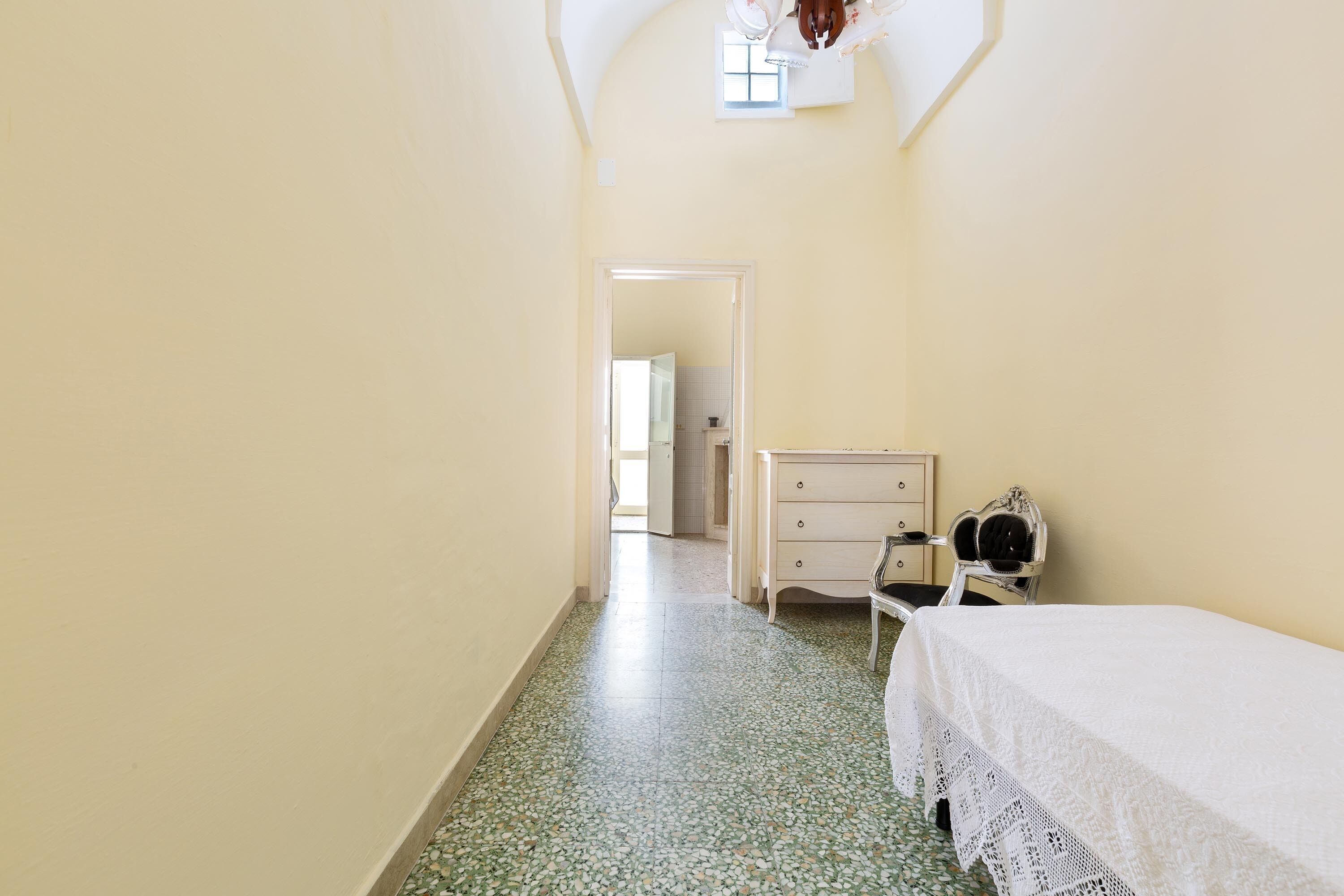 Une petite pièce comprenant un lit, une commode et une chaise.