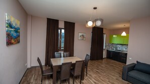 A modern living room with a dining area, a kitchen, and a sofa.