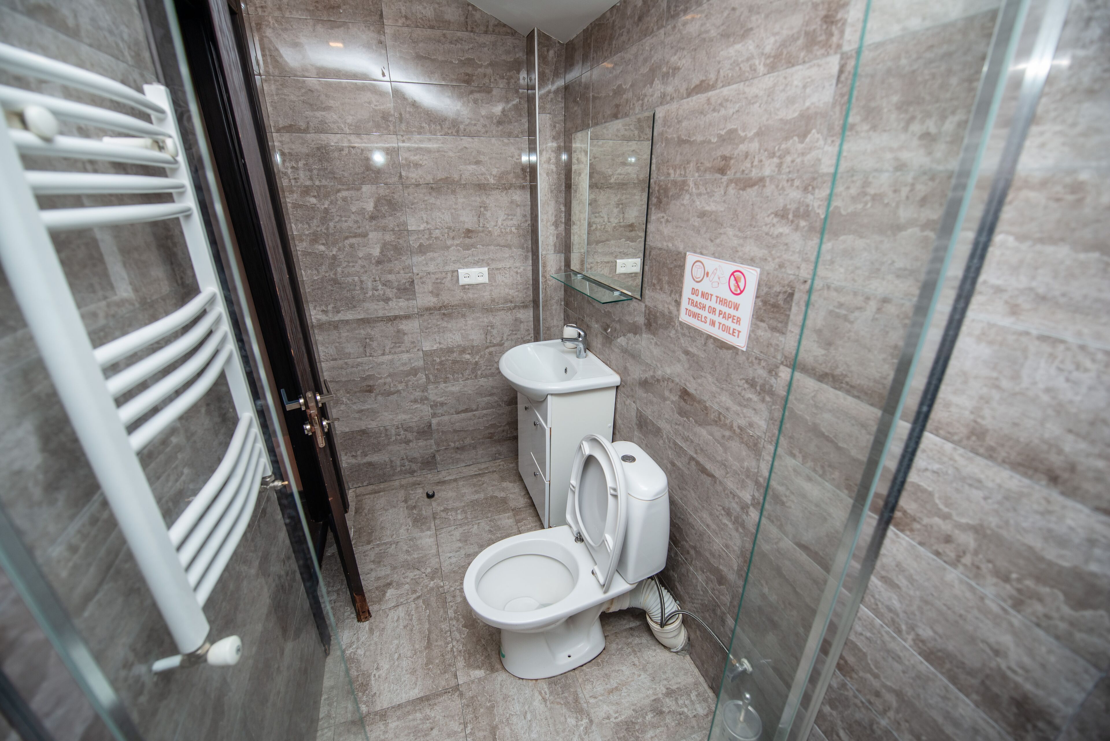 Une salle de bain moderne avec une douche à parois de verre, des toilettes blanches et un lavabo.