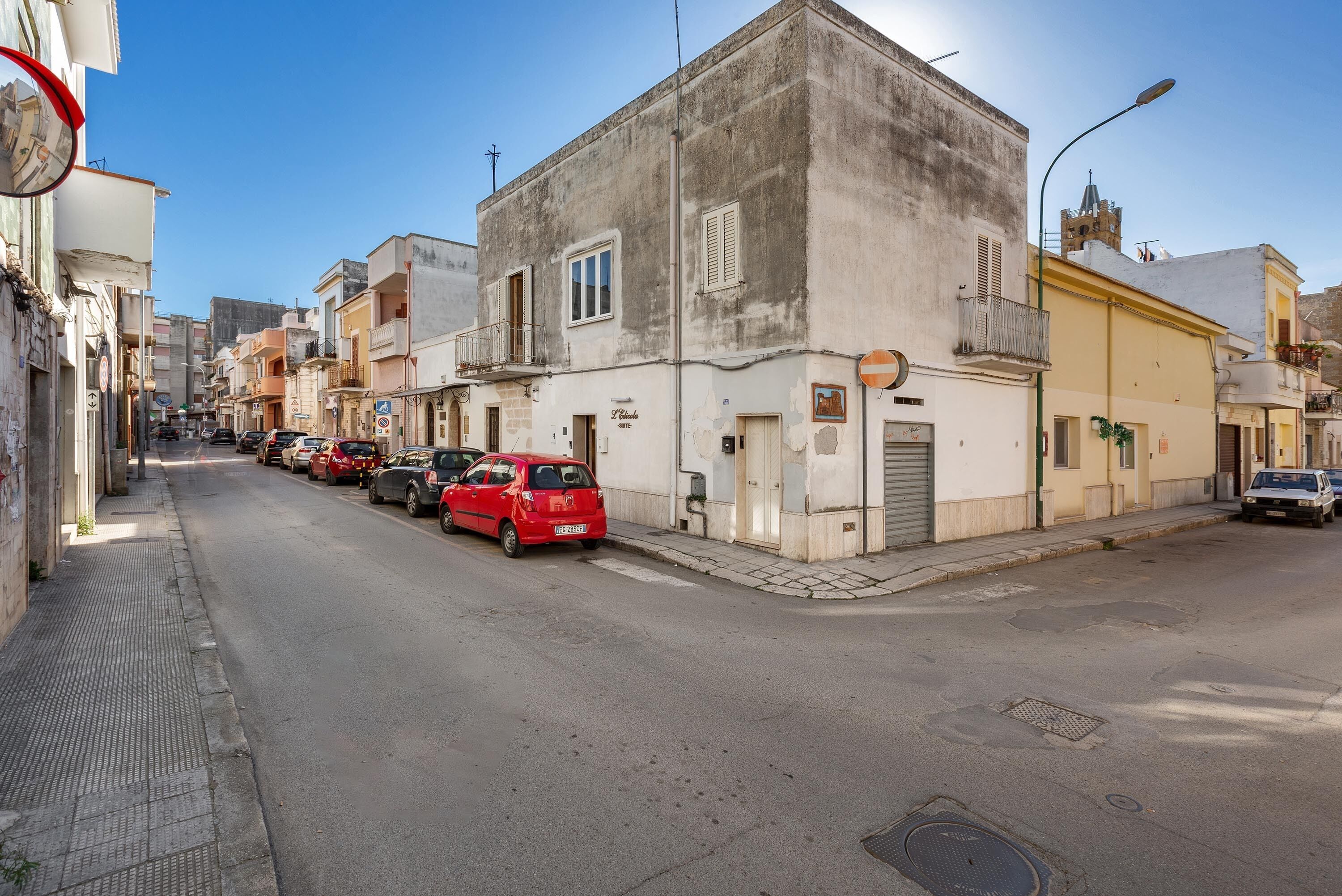 Una calle estrecha bordeada de edificios, algunos con balcones y rótulos.