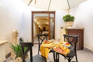Un comedor con una mesa dispuesta para cuatro, una planta en maceta y vistas a un corredor con arcos.
