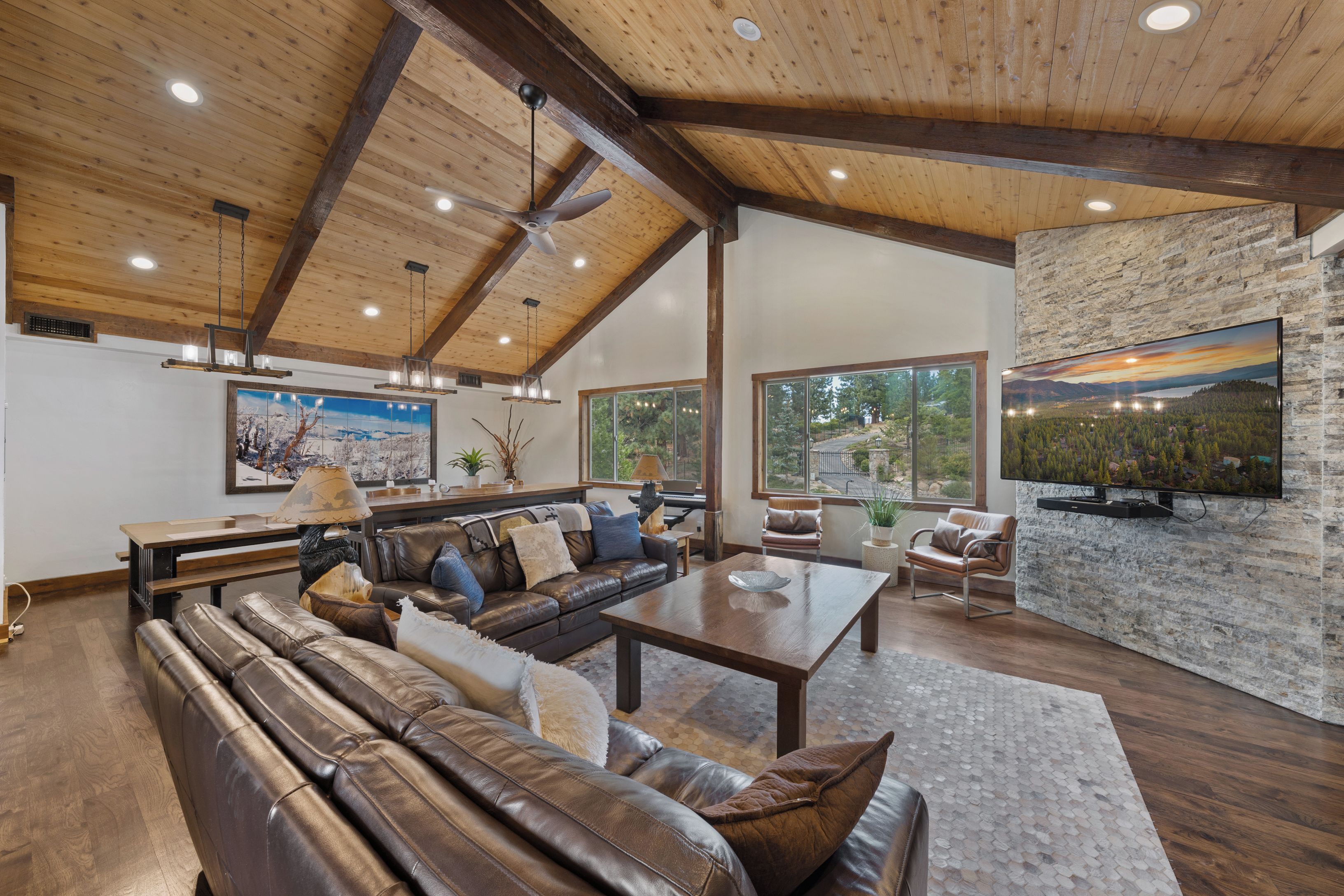 A spacious living room with a leather sofa, a wooden coffee table, and a stone fireplace.