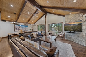 A spacious living room with a leather sofa, a wooden coffee table, and a stone fireplace.